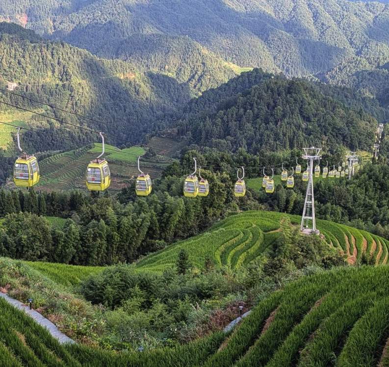Yellow cable-car cabins crossing above the Jinkeng Dazhai rice terraces on the Longji ropeway